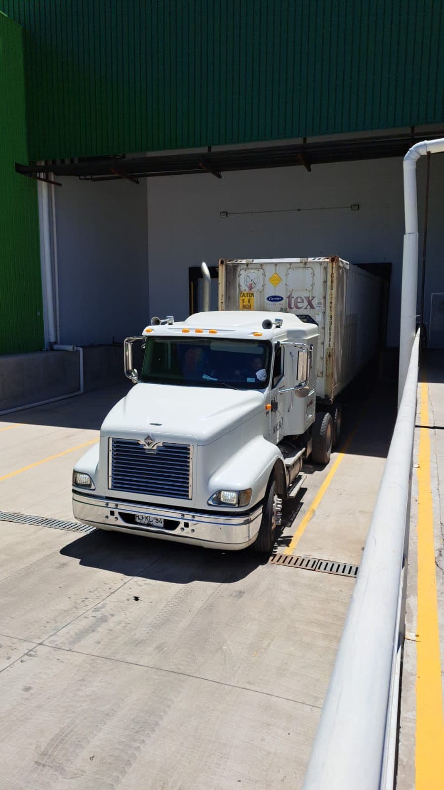 Camión con contenedor refrigerado en el andén de carga de la planta